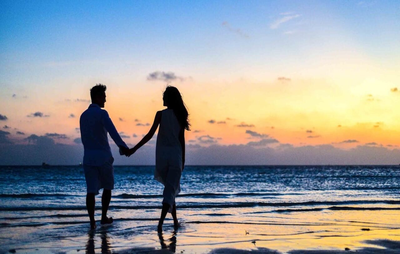 Romance | Pareja disfrutando de una caminata romántica al atardecer de una playa en Perú.