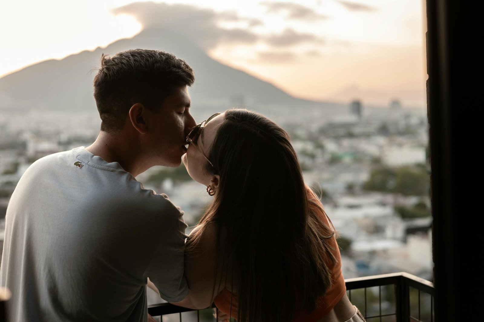 Pareja besándose con una vista panorámica de montañas al fondo, perfecta para una luna de miel en Perú.