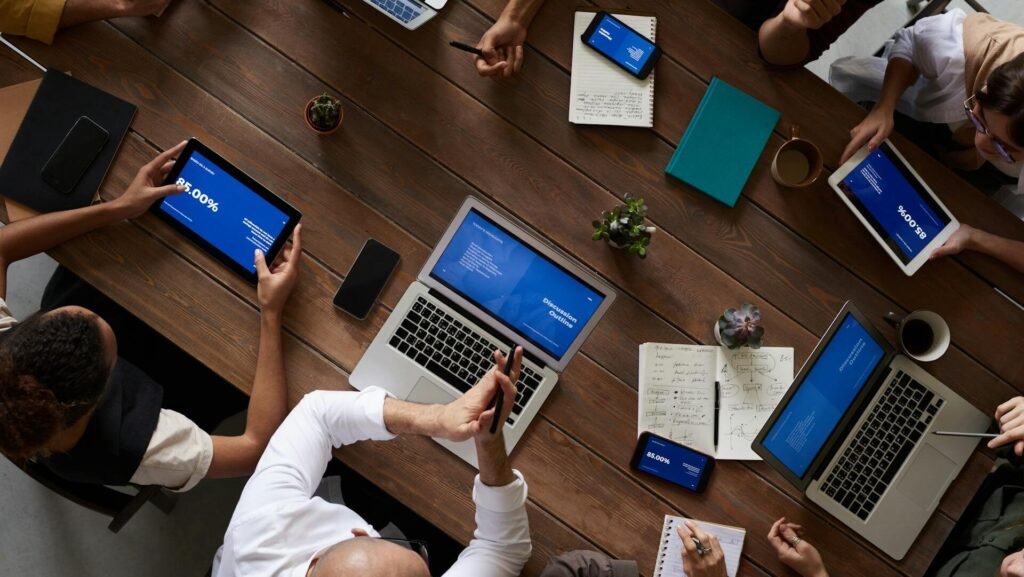 Personas trabajando en equipo en una mesa con laptops en un ambiente profesional