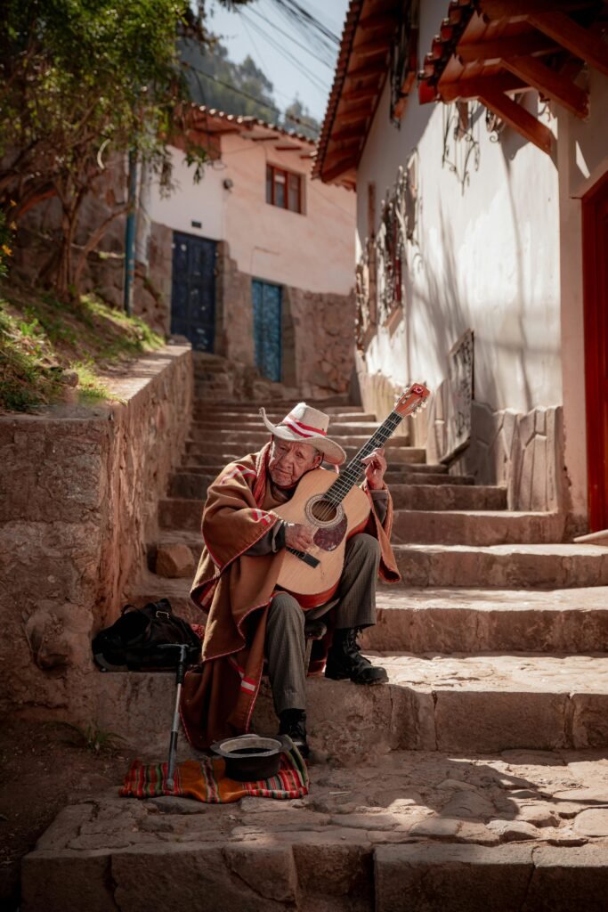 Músico tradicional peruano tocando la guitarra en las calles de Cusco, vestido con un poncho.