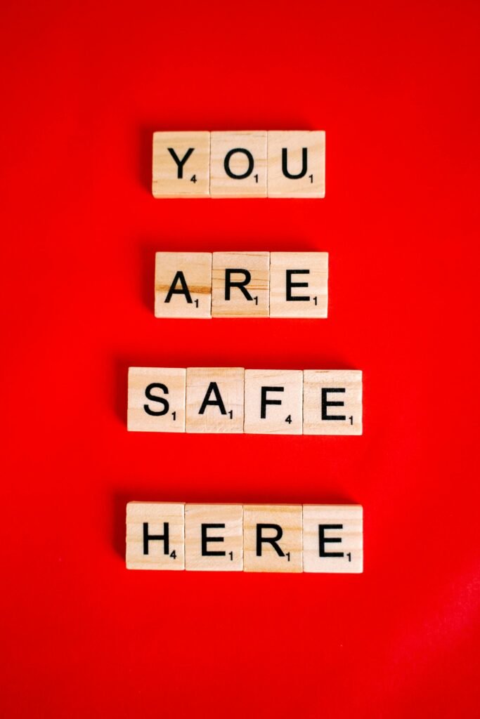 Letras de Scrabble formando las palabras 'YOU ARE SAFE HERE' sobre fondo rojo