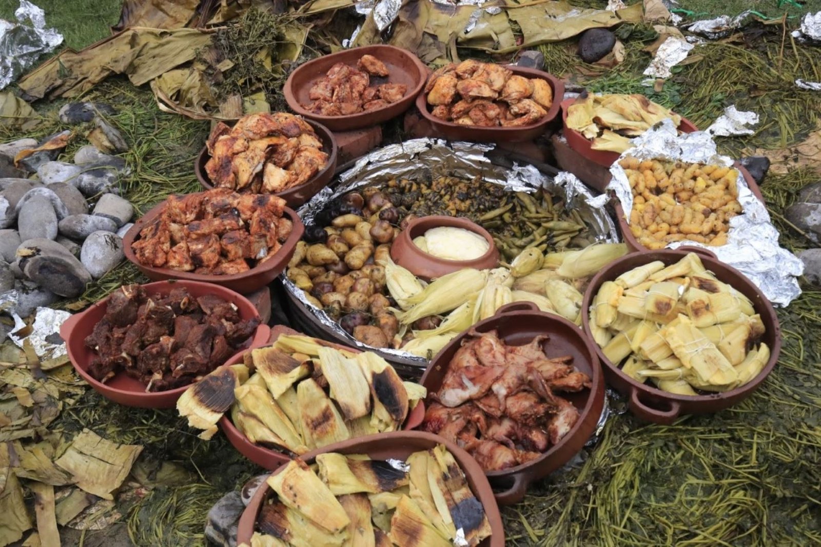 Pachamanca tradicional andina servida en platos de barro mostrando diversas carnes, maíz, papas y verduras cocinadas bajo tierra en Patabamba, Cusco.