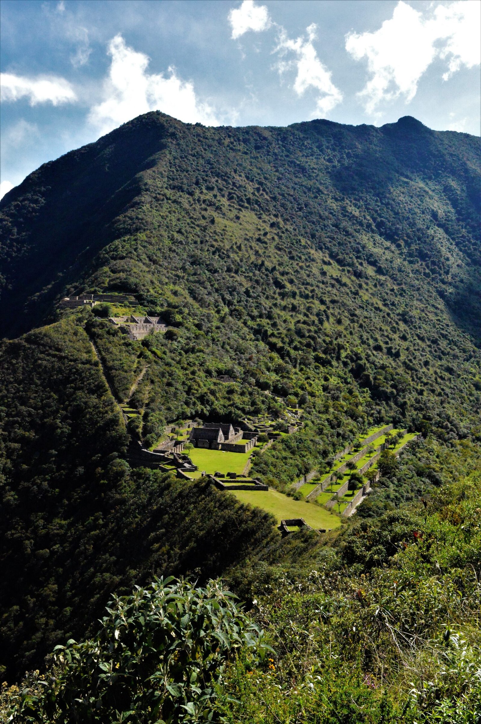 Vista panorámica de Choquequirao desde las alturas con montañas verdes de fondo