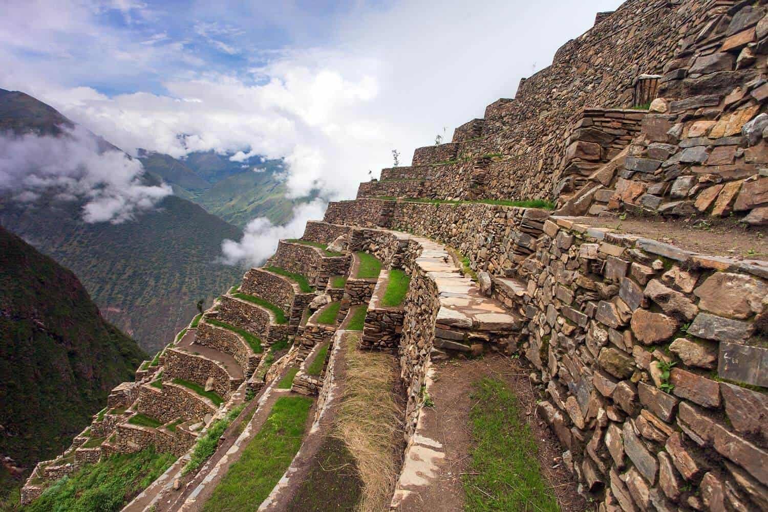 Impresionantes terrazas agrícolas incas de piedra perfectamente conservadas en Machu Picchu, con caminos serpenteantes y vista panorámica del valle cubierto de nubes