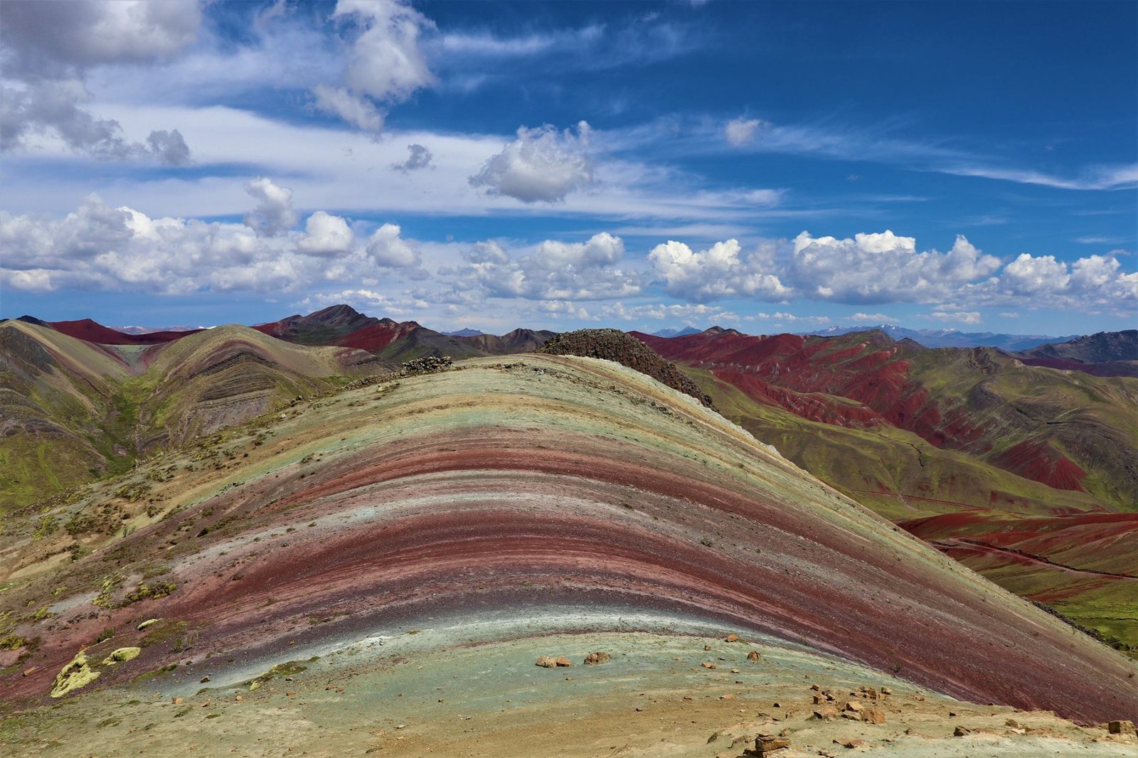 Vista panorámica de la Montaña Arcoíris de Palcoyo mostrando sus capas geológicas de colores bajo un cielo azul intenso