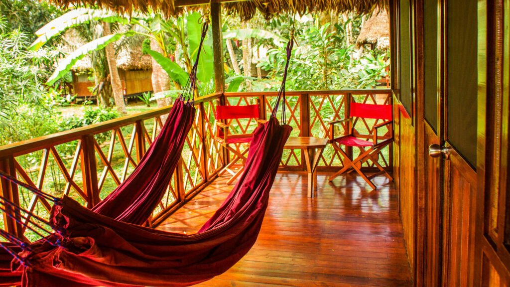 Terraza del lodge amazónico con hamacas rojas y vista panorámica a la selva tropical en Puerto Maldonado