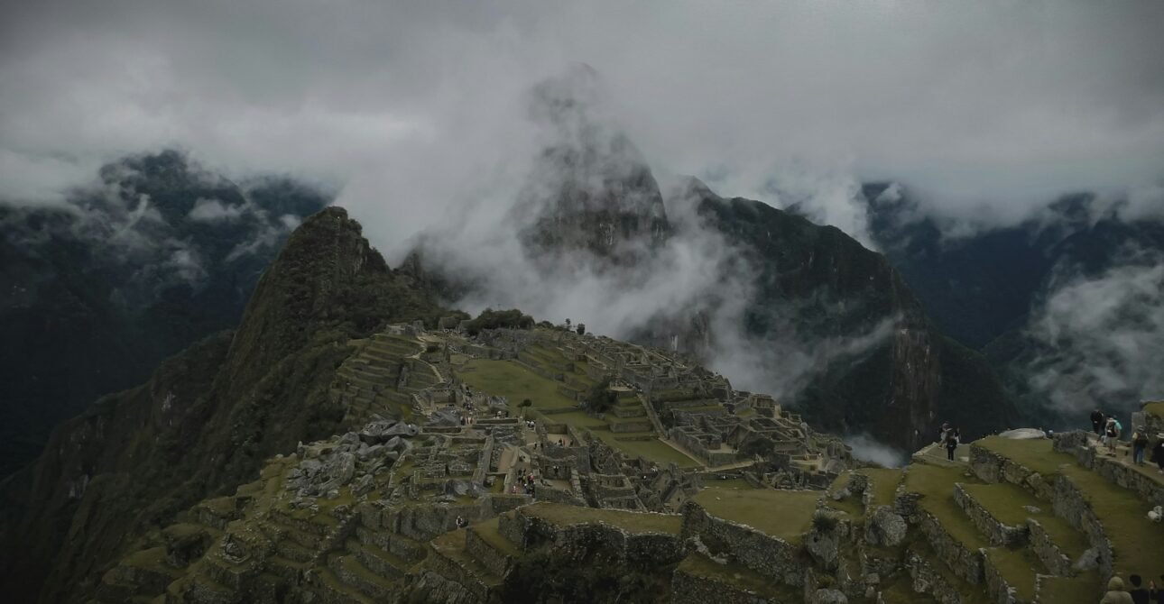 Machu Picchu envuelto en niebla matutina con turistas explorando