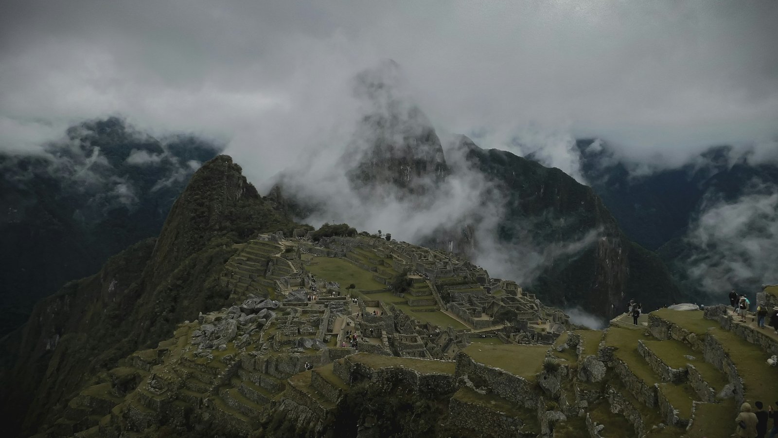 Machu Picchu envuelto en niebla matutina con turistas explorando