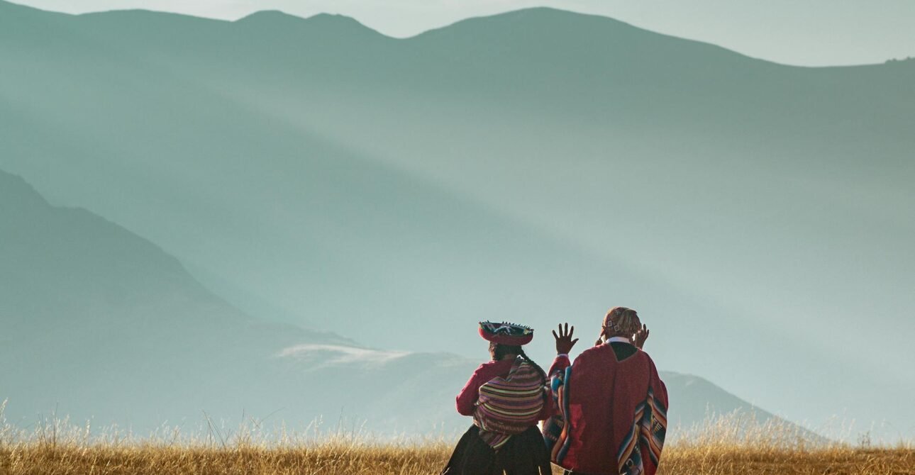 Personas con vestimenta tradicional andina contemplando paisaje montañoso