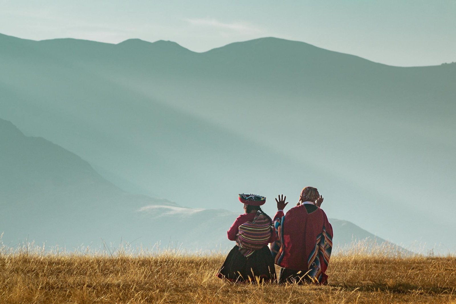 Personas con vestimenta tradicional andina contemplando paisaje montañoso