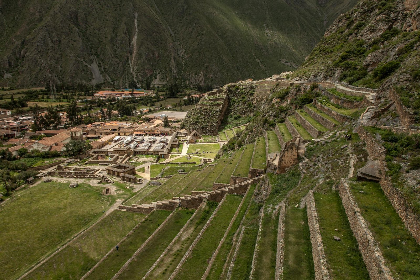 Vista panorámica del sitio arqueológico de Ollantaytambo y el pueblo con terrazas incas y montañas andinas