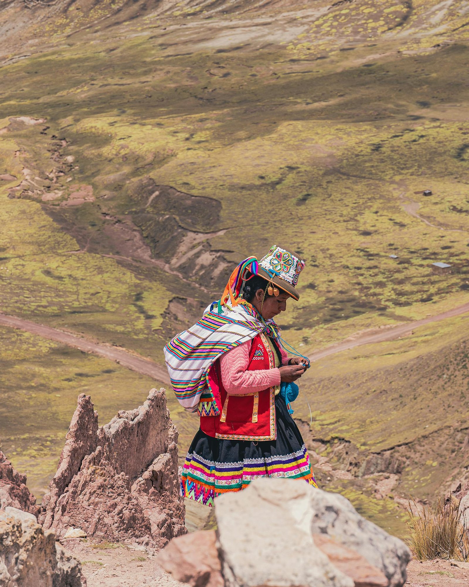 Mujer andina con vestimenta tradicional multicolor tejiendo en las alturas de Palcoyo, Cusco