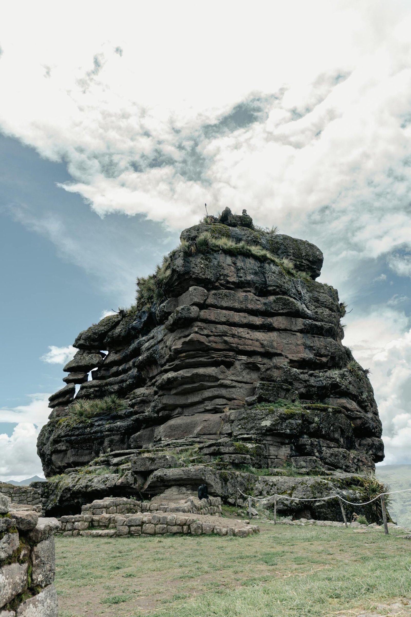 Formación rocosa principal de Waqrapukara con estructuras prehispánicas y escaleras de piedra bajo cielo nublado